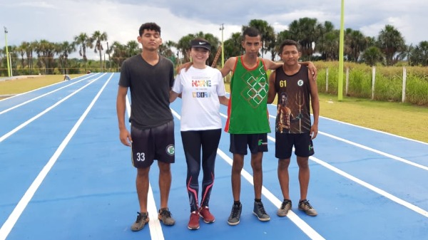 Professora Raquel posa para foto com outros três alunos em pista de atletismo azul e faixas brancas inaugurada na cidade de Lábrea, no sul do Amazonas; ao fundo, mata verde e árvores