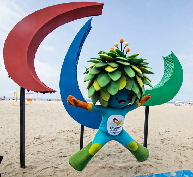 Nas areias da praia de Copacabana, no Rio de Janeiro, a mascote Tom pula de pernas e braços abertos em frente aos Agitos, símbolo dos Jogos Paralímpicos, em 2016