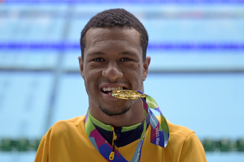 Gabriel Araújo morde medalha de ouro, sua terceira e última em Manchester | Foto: Douglas Magno/CPB